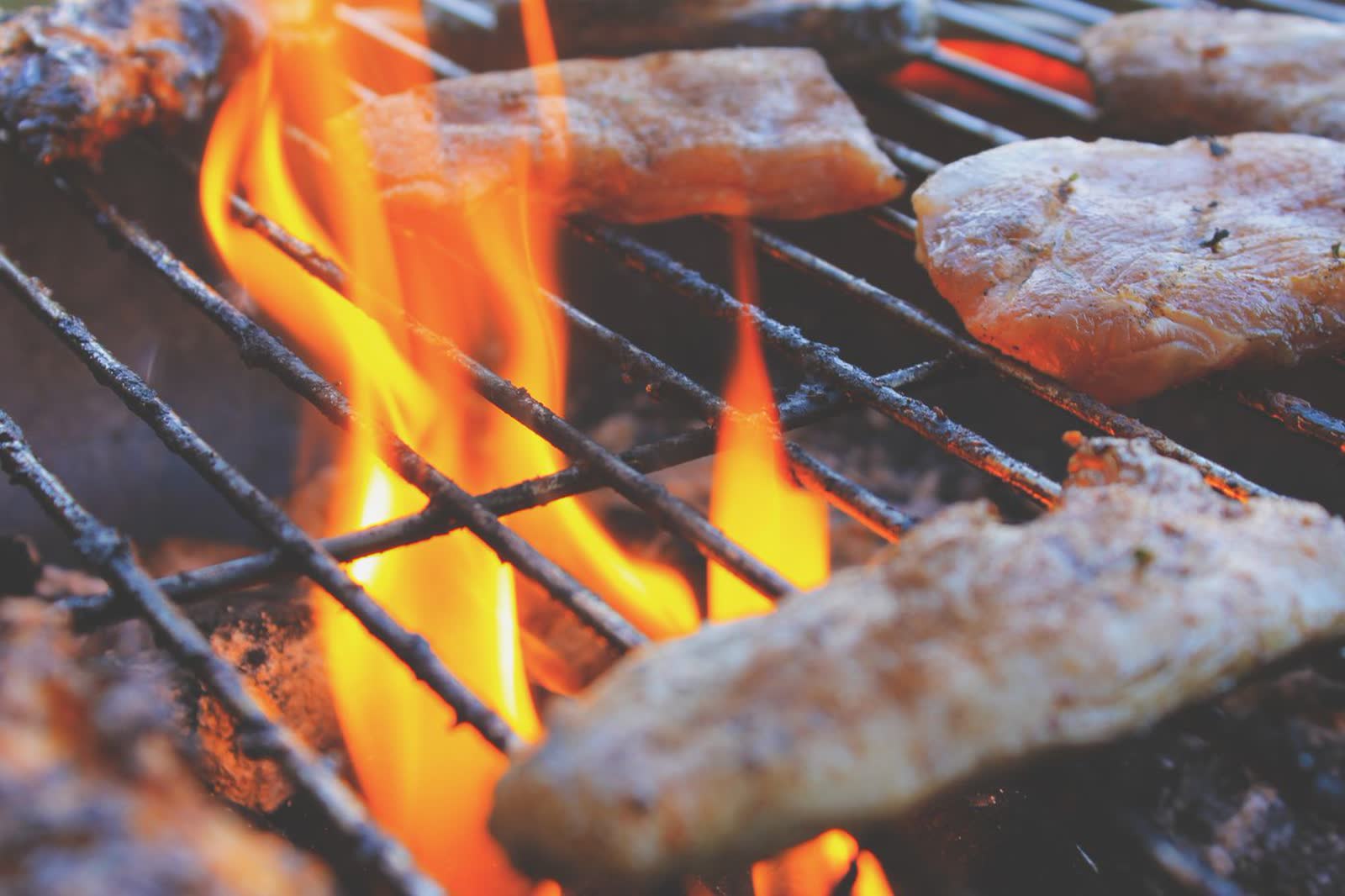Meat searing over open flame on a grill